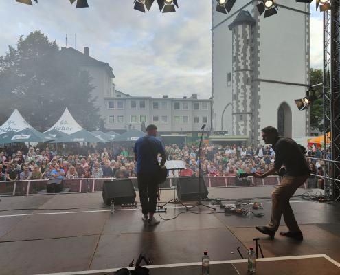 Das Bild zeigt eine Live-Performance auf einer Open-Air-Bühne dem Kirchenplatz in Gießen.