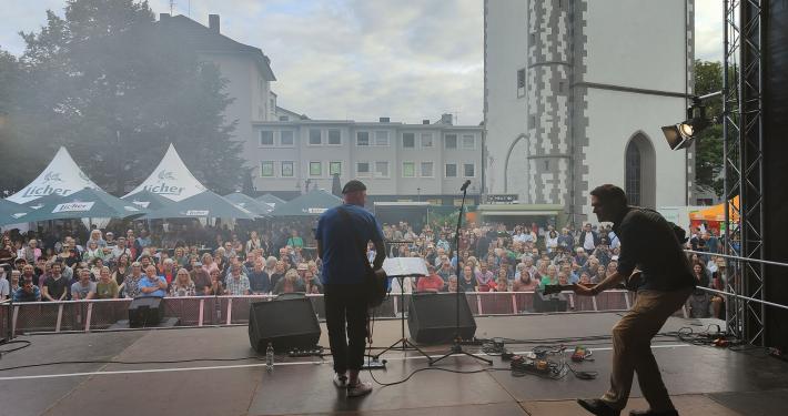 Das Bild zeigt eine Live-Performance auf einer Open-Air-Bühne dem Kirchenplatz in Gießen.