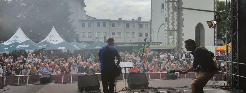 Das Bild zeigt eine Live-Performance auf einer Open-Air-Bühne dem Kirchenplatz in Gießen.